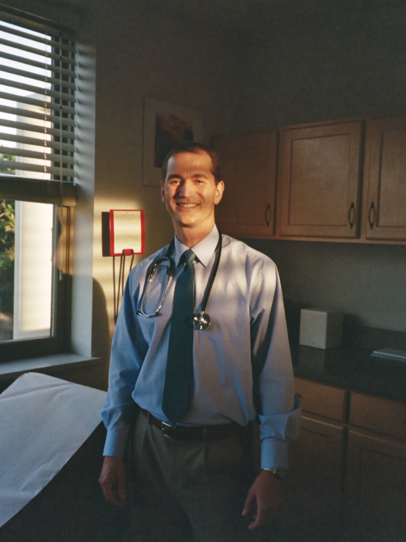 Family doctor in a shirt and tie standing in his exam room