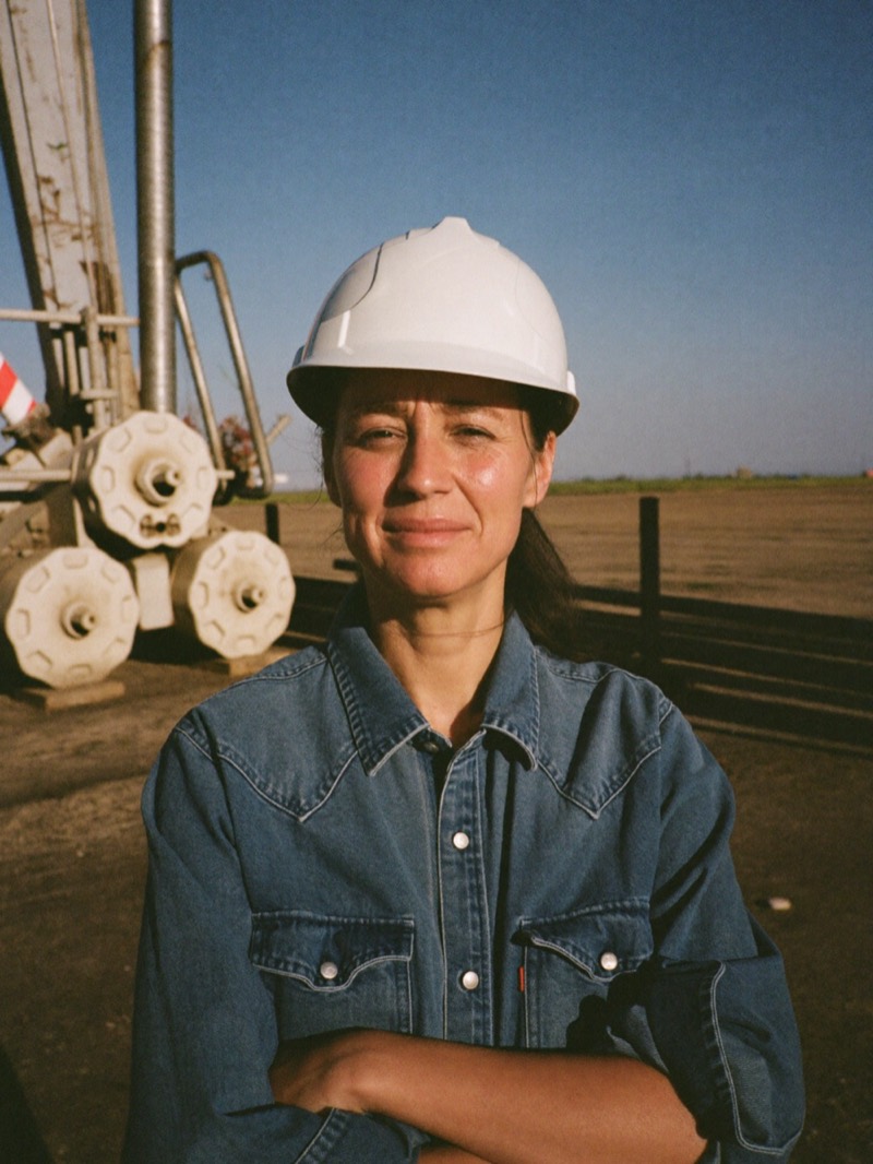 Oil field services owner in a hard hat beside pump equipment